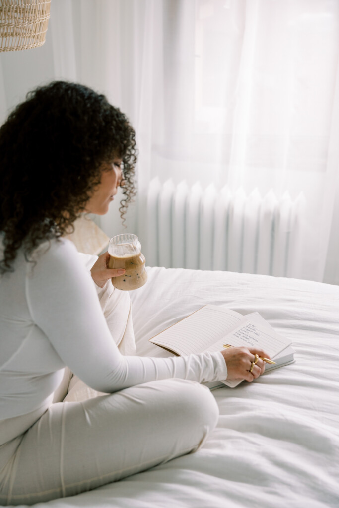 Woman journaling in a calm bedroom setting, symbolizing reflection and clarity in metabolic health decision-making.