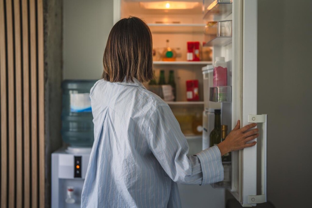 women craving sweets looking in the refrigerator